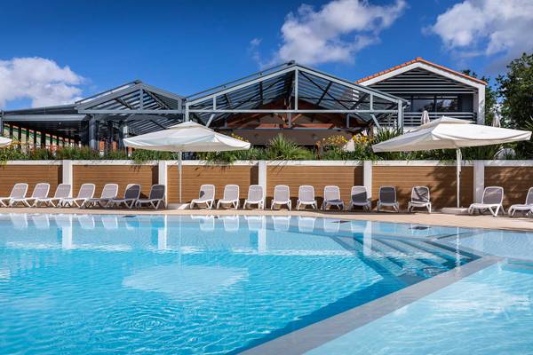 Espace piscine extérieur avec chaises longues et parasols au Camping Le Pin Parasol.