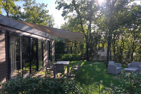 Outdoor-Sitzbereich im Barco Reale Campingplatz mit Tisch und Stühlen unter einem Sonnensegel.