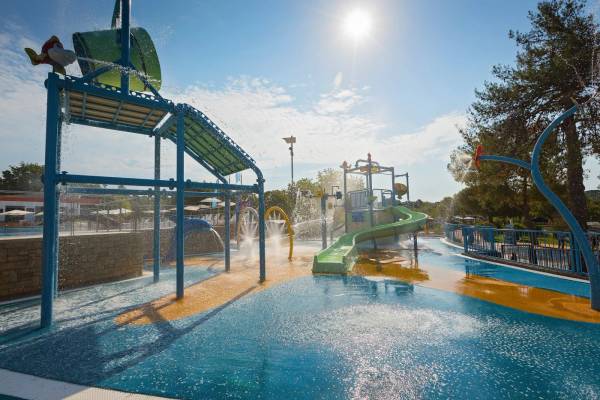 Aire de jeux aquatiques au Camping Vestar avec des toboggans et des éclaboussures par une journée ensoleillée.