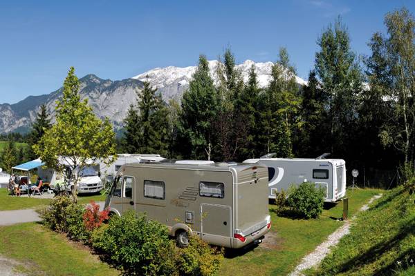 Campingplatz Ferienparadies Natterer See mit Wohnmobilen und Bergen im Hintergrund.