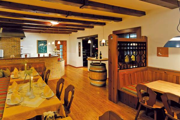 Innenbereich eines Restaurants im Ferienparadies Natterer See mit Holztischen, Stühlen und Dekorationen.