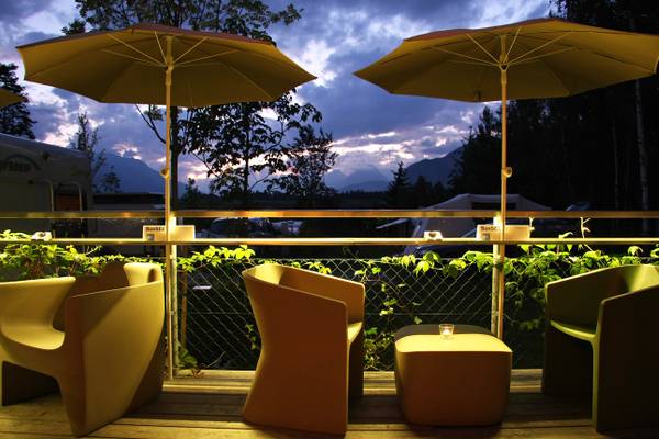 Terrasse im Ferienparadies Natterer See mit Sonnenschirmen bei Sonnenuntergang.