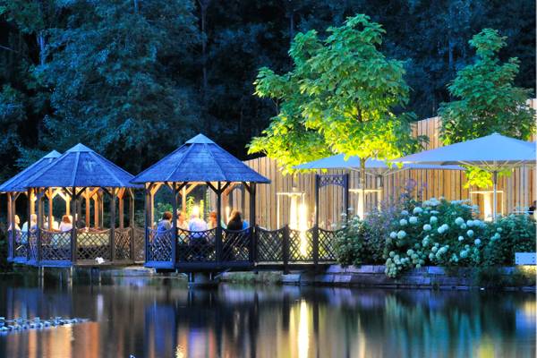Abendliche Ansicht des Natterer See Campingplatzes mit Menschen, die in Gazebos am See essen.