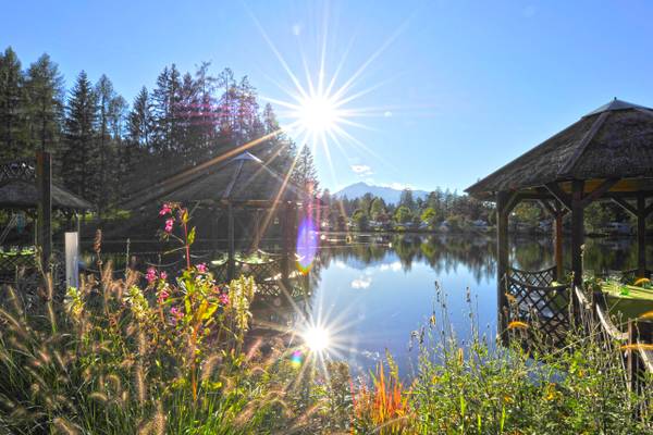 Ferienparadies Natterer See mit hellem Sonnenlicht über einem See mit Pavillons.