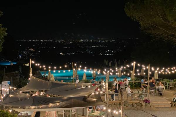 Campingplatz Barco Reale bei Nacht mit Pool, Gästen und Stadtlichtern im Hintergrund.