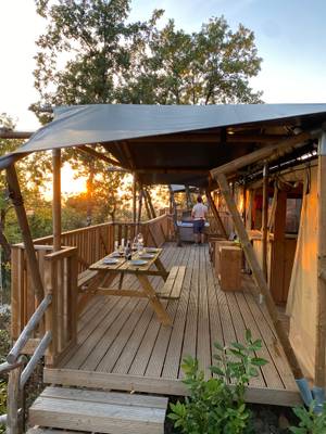 Luftaufnahme einer Campingterrasse mit Holzboden und einer Person, die grillt.