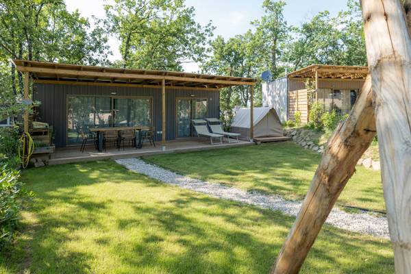 Campingplatz Barco Reale mit einer modernen Hütte und einem Zelt an einem sonnigen Tag.