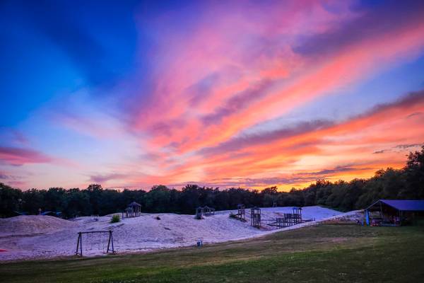 Sunset view of Camping De Paal with sand dunes and playground structures
