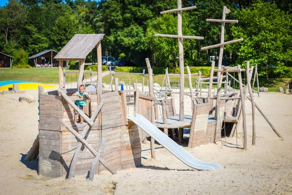 Ein junger Junge auf dem Spielplatz am Strand im Camping De Paal.