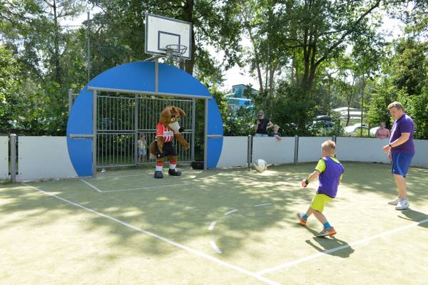 Ein Maskottchen und ein Kind spielen Fußball auf dem Campingplatz De Paal.