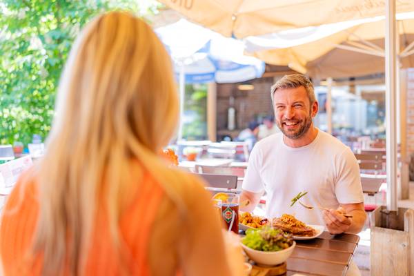 Un homme et une femme déjeunent dans un restaurant en plein air au Holmernhof Dreiquellenbad Kur- & Feriencamping.