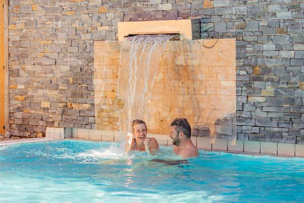 Un homme et une femme jouant dans une piscine sous une cascade au camping Holmernhof.