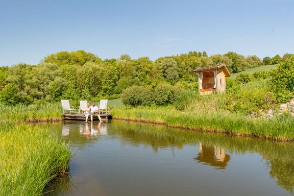 Un couple assis sur un bateau dans la piscine extérieure du camping Holmernhof.