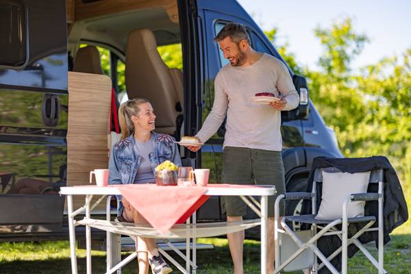 Un couple mange à l'extérieur près d'un camping-car.