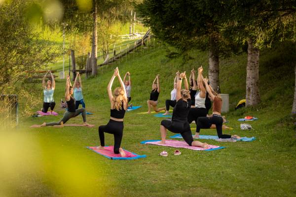 Corso di yoga al campeggio Sportcamp Woferlgut con partecipanti su tappetini.