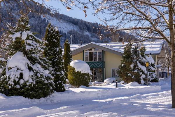 Campeggio innevato di Sportcamp Woferlgut con alberi e una casa.