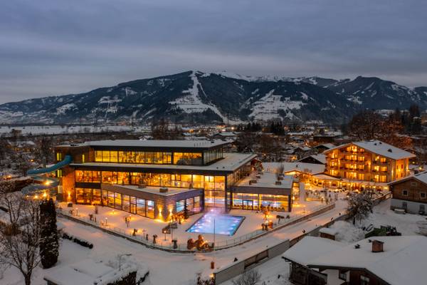 Vista aerea del Sportcamp Woferlgut di notte con una piscina e edifici nella neve.