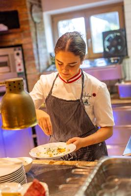 Donna in cucina al Sportcamp Woferlgut che prepara un pasto.
