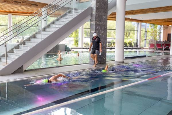 Nuotatori in una piscina al Sportcamp Woferlgut con un allenatore sul lato.
