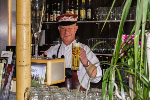 Mann im LuxOase Freizeitpark mit Bierglas hinter einer Bar.