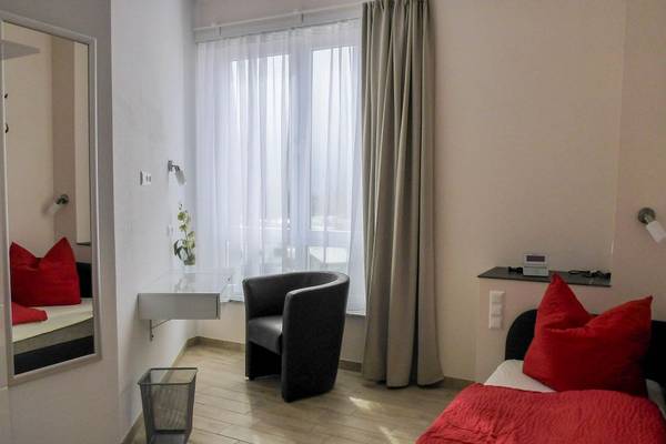 Schlafzimmer im LuxOase Freizeitpark Campingplatz mit roten Kissen, einem Stuhl und einem Bett.