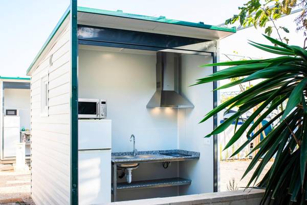 Un petit espace cuisine dans un hébergement de camping avec un évier, un micro-ondes et une cuisinière.
