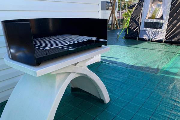 Gril sur une terrasse de camping avec une tente en arrière-plan.