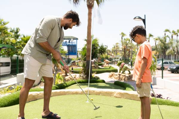 Un homme et un garçon jouent au mini-golf au camping La Marina Camping & Resort.