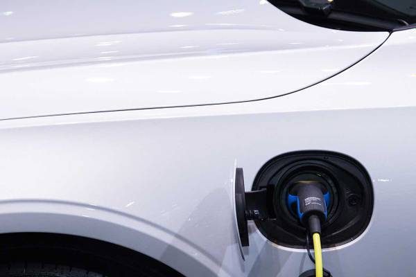 Elektroauto-oplaadstik, der er tilsluttet en hvid bil