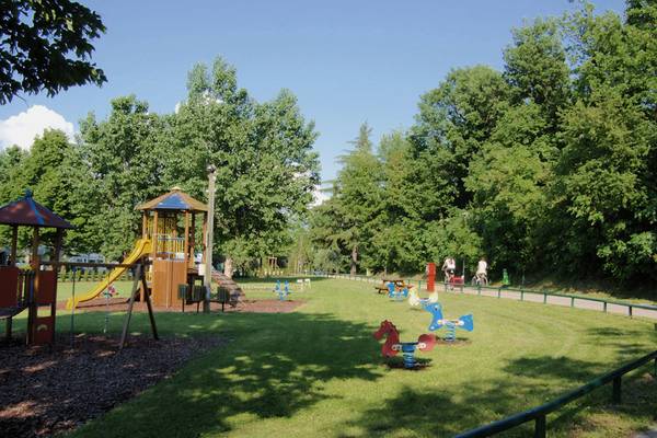 Børnelegeplads på Fornella Camping & Wellness Family Resort med rutsjebaner, svinger og bænke.