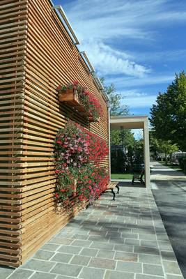 Un muro di legno con fiori appesi e un sentiero sul lato.