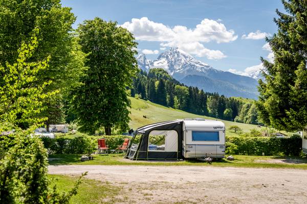 Campingplatz mit Wohnwagen und Bergen im Hintergrund.