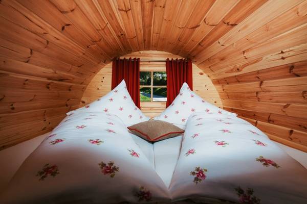 Bett im Camping Resort Allweglehen mit weißen Laken und roten Vorhängen