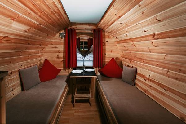 Innenbereich eines Campingresorts mit Holzwänden, zwei Betten und einem kleinen Tisch.