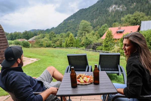 Ein Paar sitzt auf Stühlen auf einem Campingplatz mit Getränken und Essen auf einem Tisch.