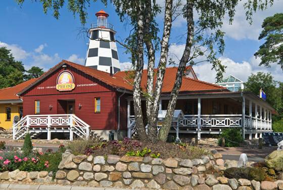 Südsee-Camp Pier One bygning med et fyrtårn på toppen, omgivet af træer og blomster.