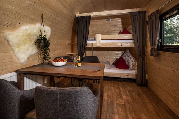 Innenansicht eines Blockhauses im Camping Resort Allweglehen mit Esstisch und Etagenbetten.