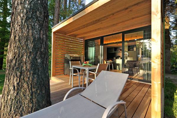 Terrasse des Ferienparadies Natterer See Campingplatz mit Tisch, Stühlen und Grill.