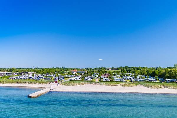 Luftfoto af Insel-Camp Fehmarn camping med mange autocampere parkeret langs stranden.