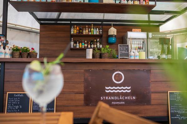 Bar de cócteles en Strandlacheln en Fehmarn con bebidas y menú en pizarras.