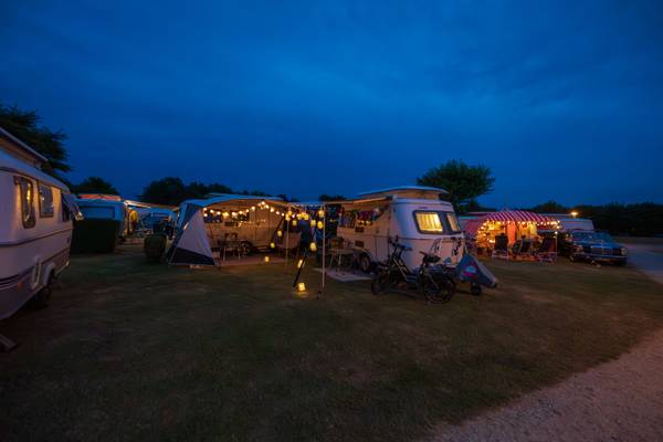 Vista nocturna del camping Insel-Camp Fehmarn con autocaravanas y tiendas iluminadas.