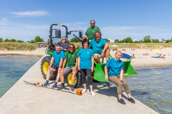 El equipo de Insel-Camp Fehmarn posa frente a un vehículo verde en la playa