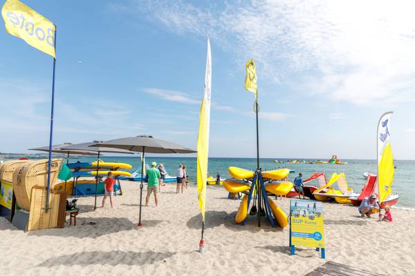 Una playa con sombrillas y barcos en el camping Insel-Camp Fehmarn.