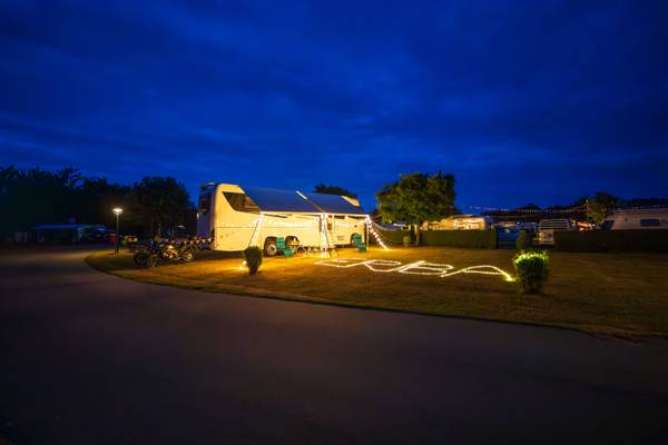 Campamento Insel-Camp Fehmarn de noche con una autocaravana y letras iluminadas