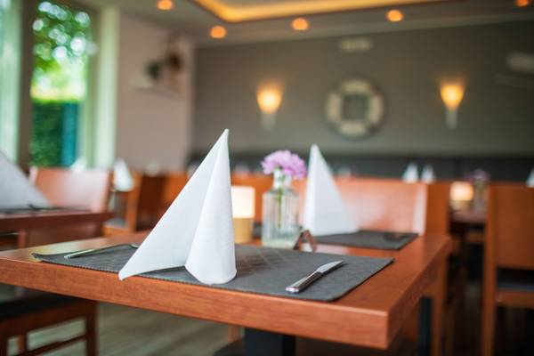 Mesa de restaurante en Insel-Camp Fehmarn con manteles, servilletas y cubiertos.