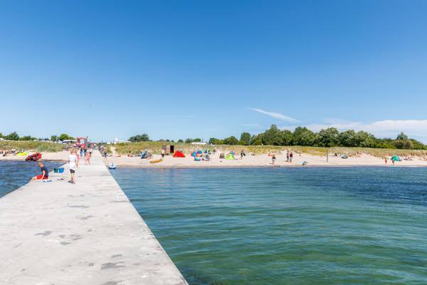 Vista de la playa en el camping Insel-Camp Fehmarn con personas y tiendas.