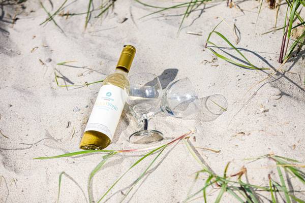 Una botella y dos vasos en la arena de la playa.