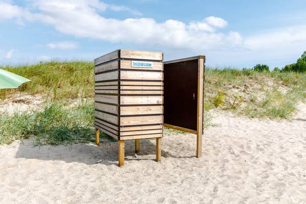 Pequeña cabina de cambio en la playa con la puerta abierta en un día soleado