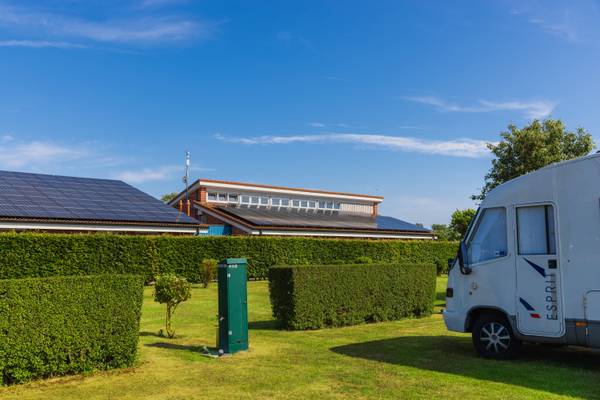 Camping Insel-Camp Fehmarn con paneles solares y autocaravana en primer plano.