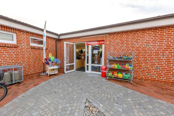 Entrada frontal del camping Insel-Camp Fehmarn con puertas abiertas y un letrero de tienda.